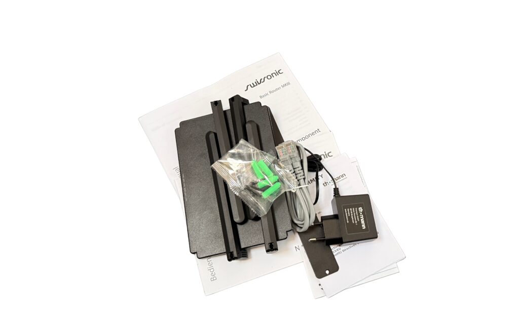Alles, was drin ist: Swissonic Basic Router MKIII, 90-cm-Netzwerkkabel, Manual, Netzteil und eine Montageplatte mit zwei Schrauben